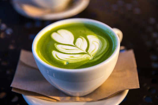 A matcha latte with leaf latte art in a white cup, made at home for a fraction of the cafe price